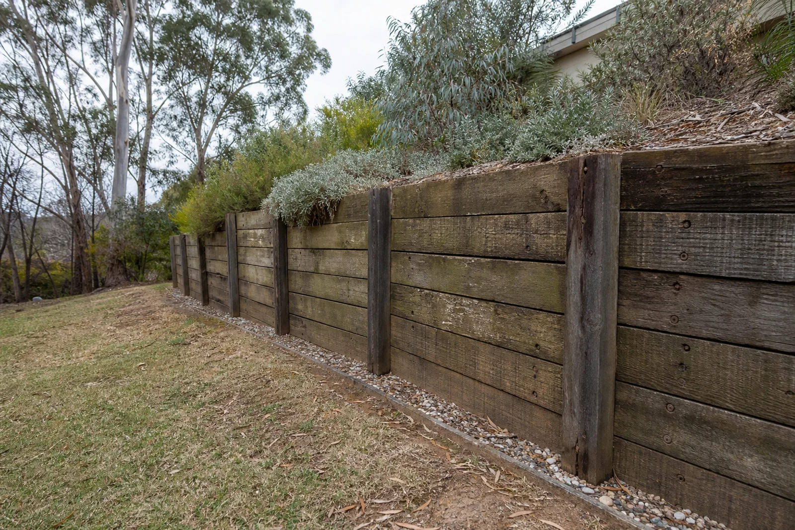 Weathered timber retaining wall on a Canberra garden slope